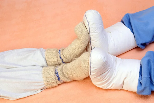 Two Couple's feet warming at a bed — Stock Photo, Image