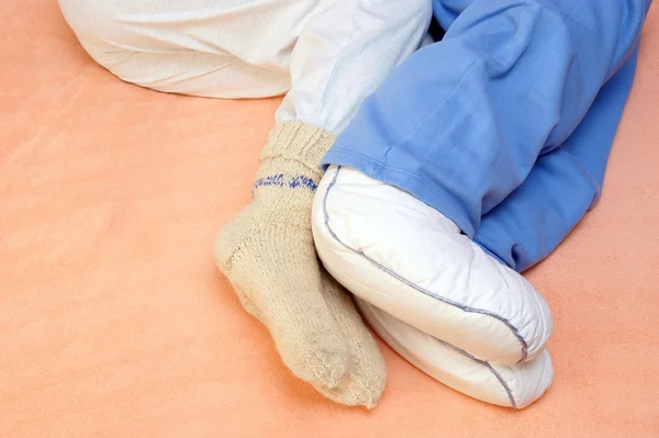 Two Couple's feet warming at a bed — Stock Photo, Image