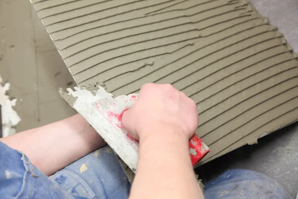 Construction worker is tiling at home tile floor adhesive — Stock Photo, Image