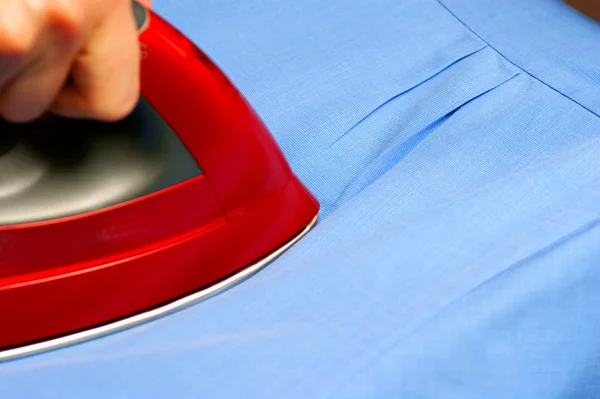 Red iron steam ironing a shirt — Stock Photo, Image