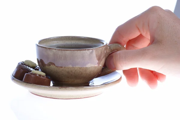 Chocolade pralines, cup, zwarte koffie en vrouwelijke hand op wit — Stockfoto