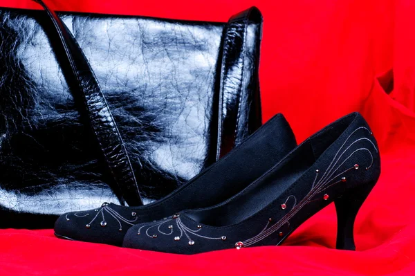 Czarny kobiece buty i torebka na czerwonym tle — Zdjęcie stockowe