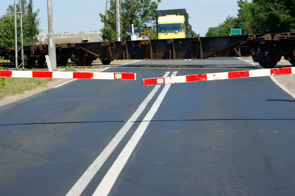 Freight train passing a railroad crossing with gates — Stock Photo, Image