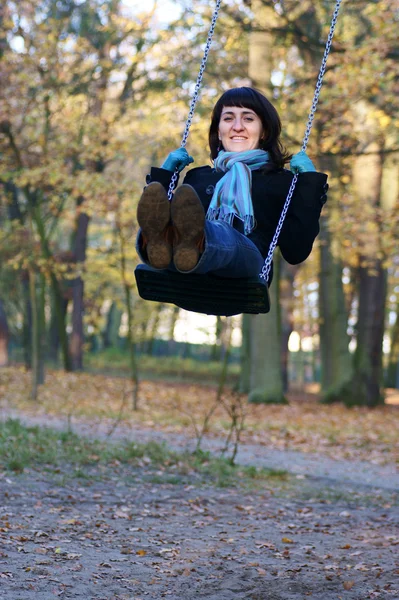 Frau in blauem Schal schaukelt auf Schaukel im Park — Stockfoto