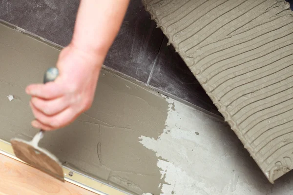 建設労働者が自宅でタイル床の接着剤をタイリングします。 — ストック写真
