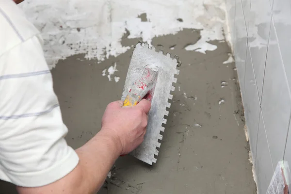 Trabalhador da construção é azulejos em casa azulejo piso adesivo — Fotografia de Stock