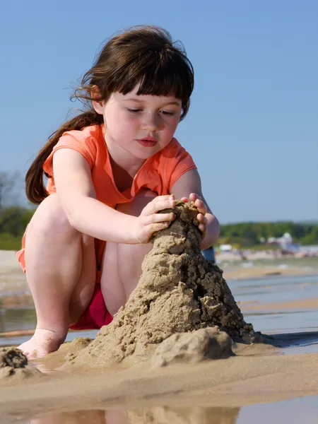 Girl on the beach making sandcastles — Stock Photo, Image