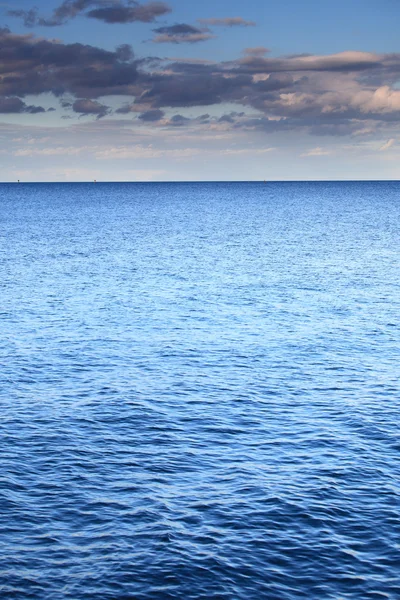 青い地平線の表面の海を残す曇りの青い空 — ストック写真