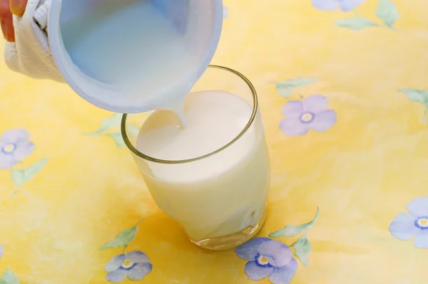 Despejando kefir para vidro, fundo amarelo — Fotografia de Stock