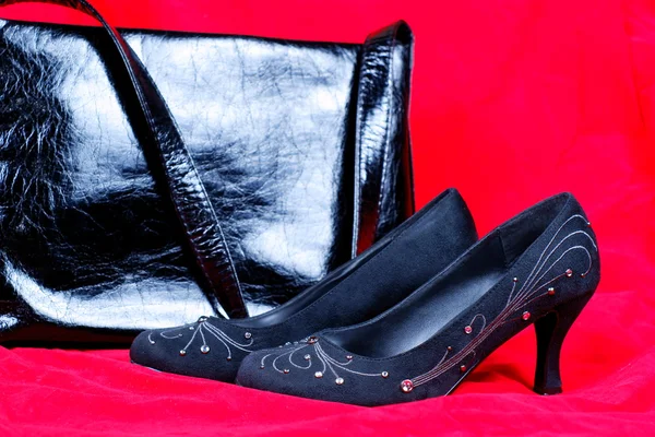 Черная женская обувь и сумка на красном фоне — стоковое фото