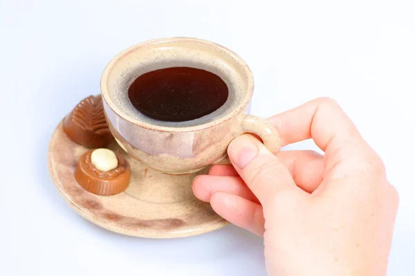 Praline al cioccolato, tazza, caffè nero e mano femminile su bianco — Foto Stock