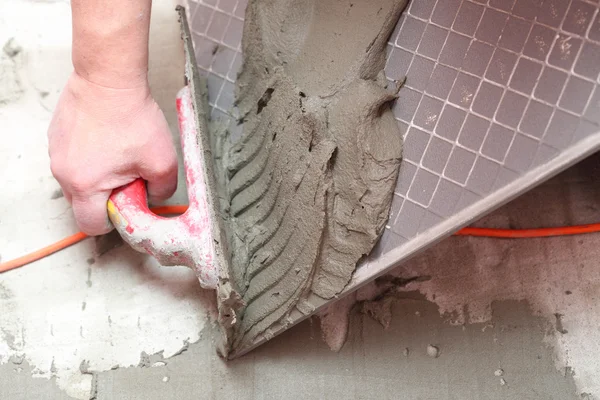 El trabajador de la construcción está embaldosando en el adhesivo de piso de baldosas — Foto de Stock