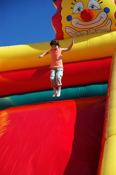 Chica saltando en la diapositiva inflable coloreada — Foto de Stock