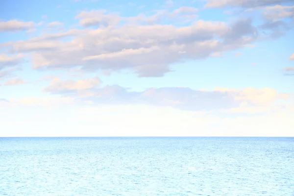 Cloudy blue sky leaving for horizon blue surface sea — Stock Photo, Image