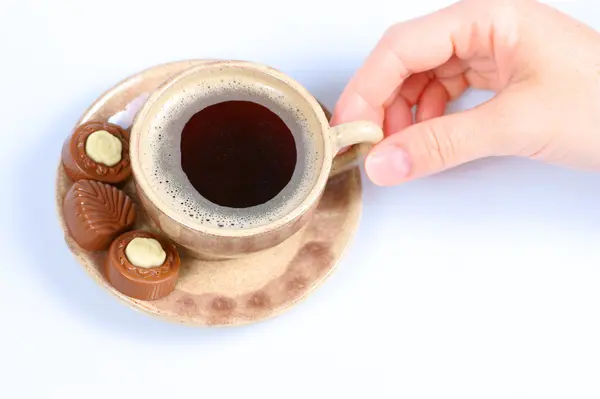 Chocolate pralines, cup, black coffee and female hand on white — Stock Photo, Image