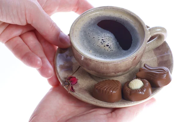 Praline al cioccolato, tazza, caffè nero e mano femminile su bianco — Foto Stock