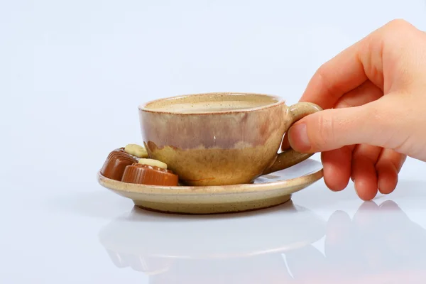 Pralinés de chocolate, taza, café negro y mano femenina sobre blanco — Foto de Stock