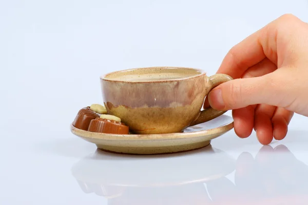 Praline al cioccolato, tazza, caffè nero e mano femminile su bianco — Foto Stock