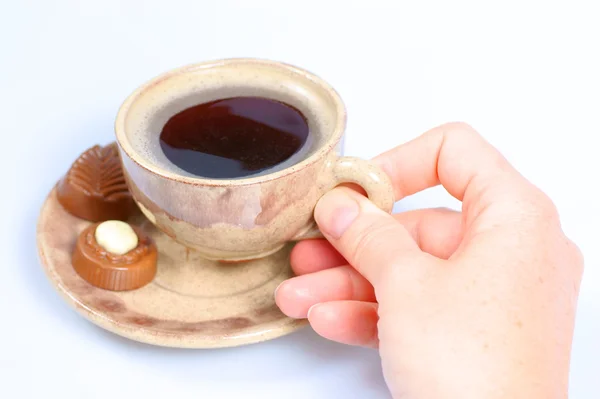 Шоколадні праліни, чашка, чорна кава та жіноча рука на білому — стокове фото