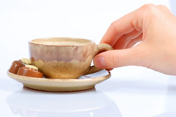 Chocolade pralines, cup, zwarte koffie en vrouwelijke hand op wit — Stockfoto