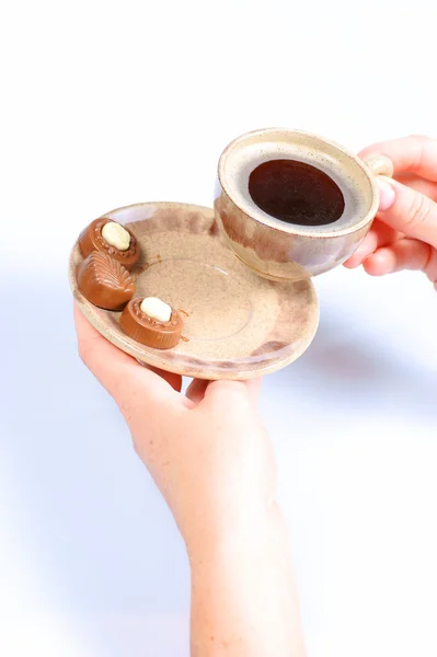 Chocolate pralines, cup, black coffee and female hand on white Stock Image