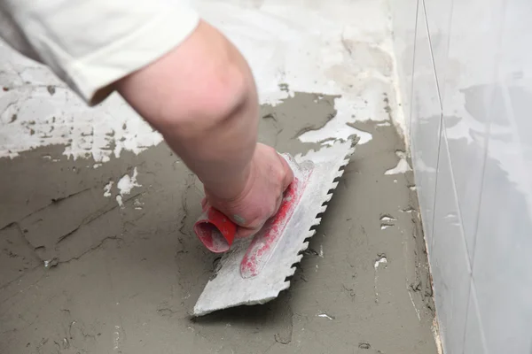 Construction worker is tiling at home tile floor adhesive — Stock Photo, Image