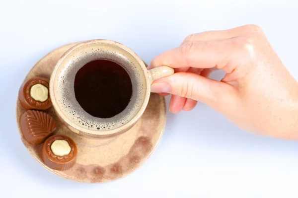 Pralinés de chocolate, taza, café negro y mano femenina sobre blanco — Foto de Stock