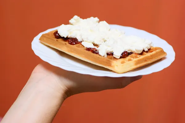 Waffle with cream and strawberry, plum jam on plate in hand — Stock Photo, Image