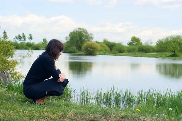 A woman sits alone and looks out across the river. Relax. — Stock Photo, Image