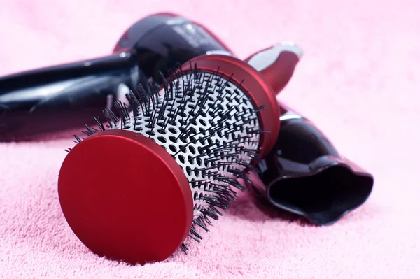Pente redondo vermelho e secador de cabelo no fundo rosa — Fotografia de Stock