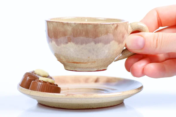 Pralinés de chocolate, taza, café negro y mano femenina sobre blanco — Foto de Stock