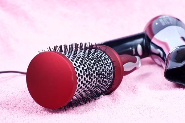 Pente redondo vermelho e secador de cabelo no fundo rosa — Fotografia de Stock