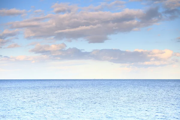 Cloudy blue sky leaving for horizon blue surface sea — Stock Photo, Image