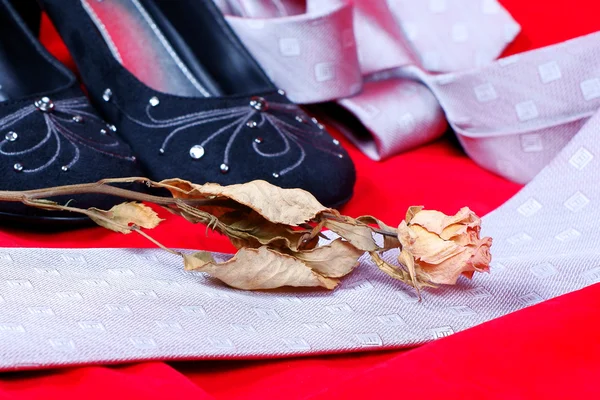 Černé ženské boty, rose a kravatu na červeném pozadí — Stock fotografie