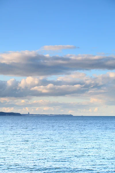 Cloudy blue sky leaving for horizon blue surface sea — Stock Photo, Image