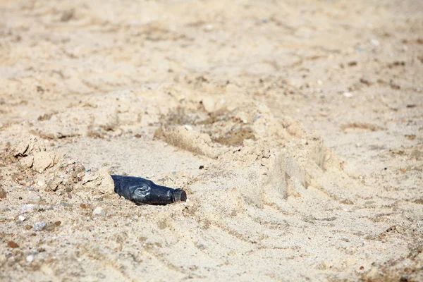 Black Plastic bottle in sand outdoor — Stock Photo, Image