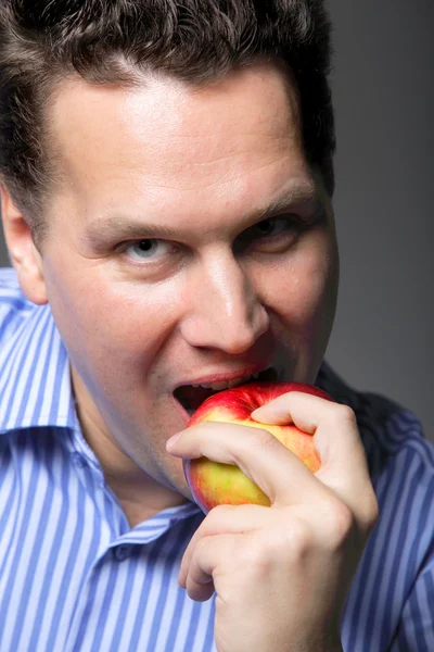 Portrait of a mature man about to eat a red apple — Stock Photo, Image