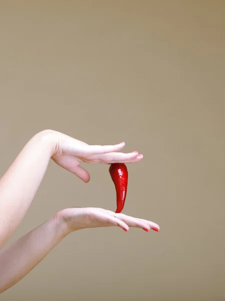 Chili peper en menselijke hand bruine achtergrond — Stockfoto