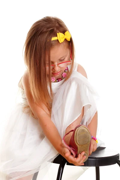 Cute little girl white dress putting on her shoe — Stock Photo, Image