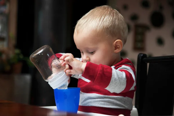 Bambino ragazzo giocare con bottiglia e tazza al coperto — Foto Stock