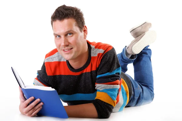 Młody człowiek czytając książkę na podłodze na białym tle — Zdjęcie stockowe