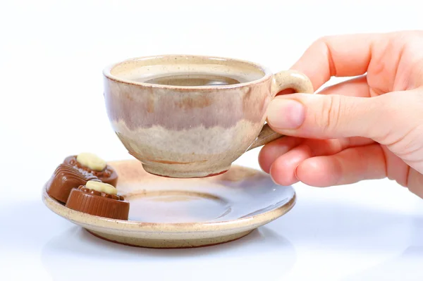 Pralinés de chocolate, taza, café negro y mano femenina sobre blanco — Foto de Stock