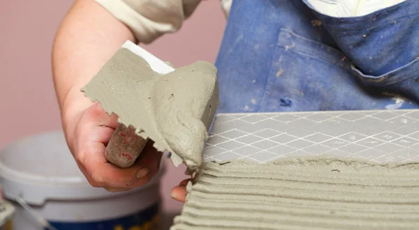 Construction worker is tiling at home tile floor adhesive — Stock Photo, Image