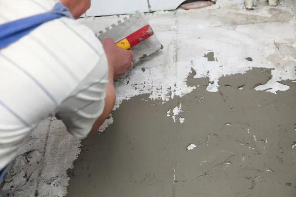 Trabalhador da construção é azulejos em casa azulejo piso adesivo — Fotografia de Stock