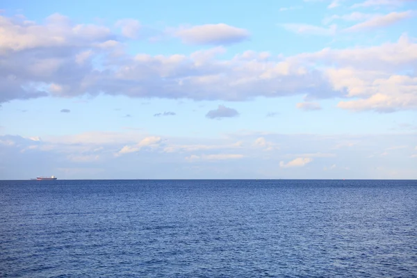 Cloudy blue sky leaving for horizon blue surface sea — Stock Photo, Image