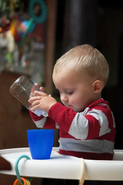 Baby boy playing with bottle and mug indoor — Stock Photo, Image