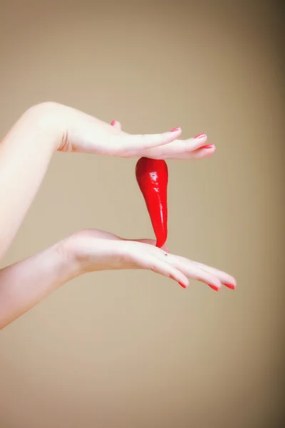 Chili pepper and human hand brown background — Stock Photo, Image