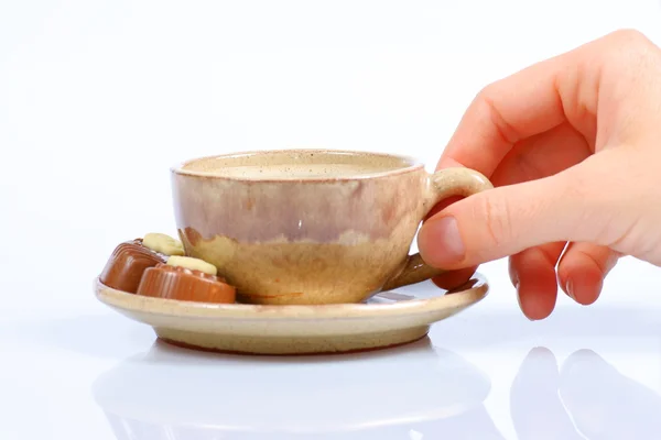 Chocolade pralines, cup, zwarte koffie en vrouwelijke hand op wit — Stockfoto