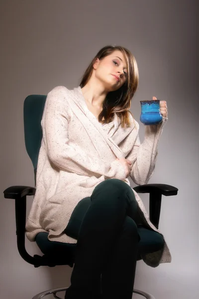 Pretty woman holding a tee cup and sits on a chair — Stock Photo, Image