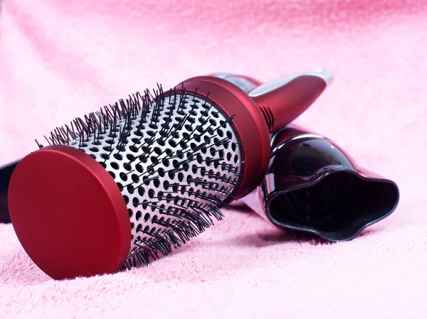 Kırmızı yuvarlak tarak ve saç kurutma makinesi gül arka plan üzerinde — Stok fotoğraf